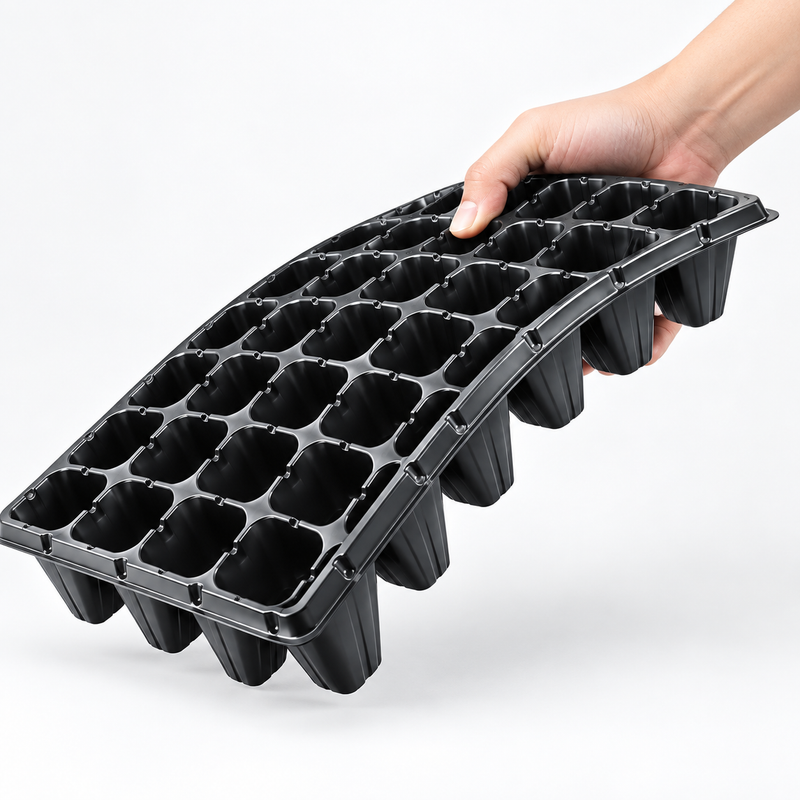 Black seedling plug tray flexed by hand to show tray resilience and handling.